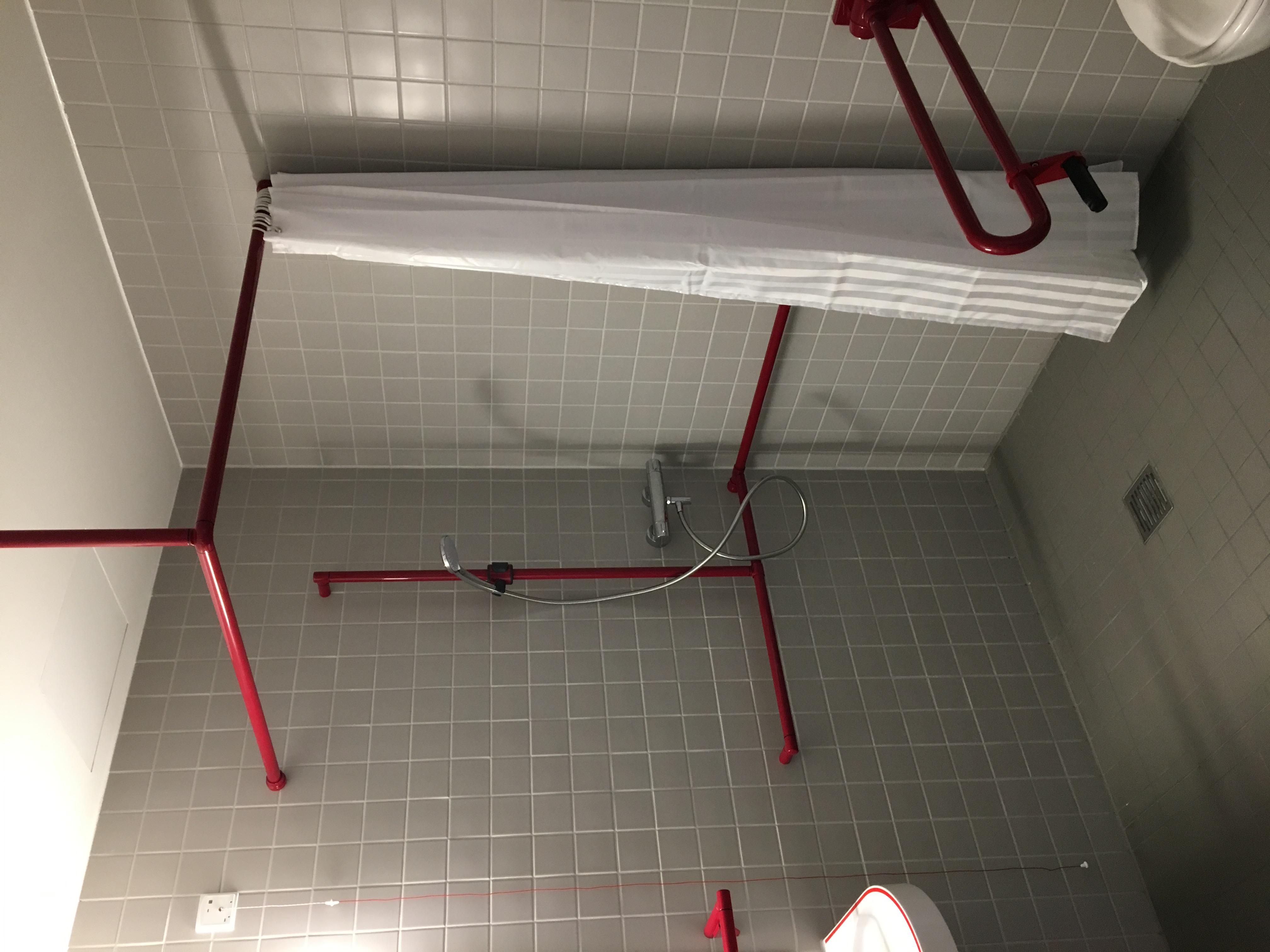 Duschvorhangstange und Duschhandlauf in Rubinrot der Marke Erlau in der Dusche im Seniorenwohnheim Unterrombach