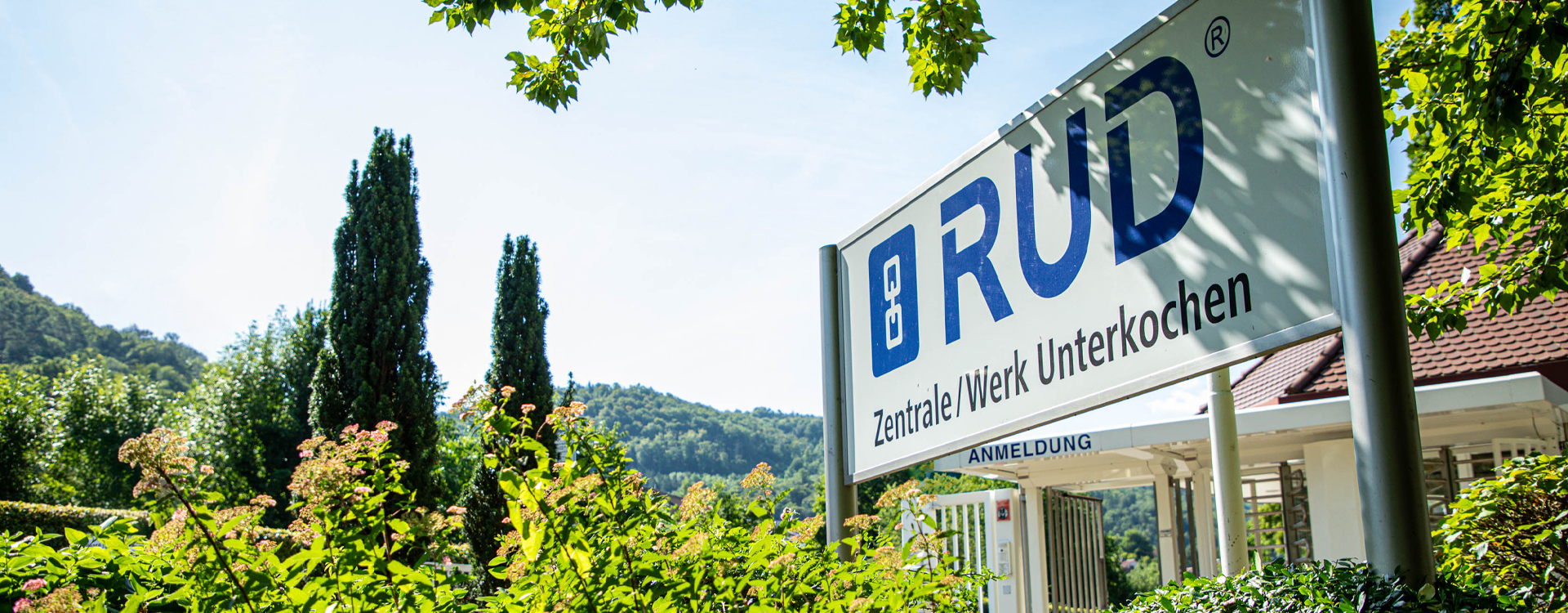 Eingangsschild der RUD-Zentrale im Werk Unterkochen mit Blick auf Natur und Grünanlagen.